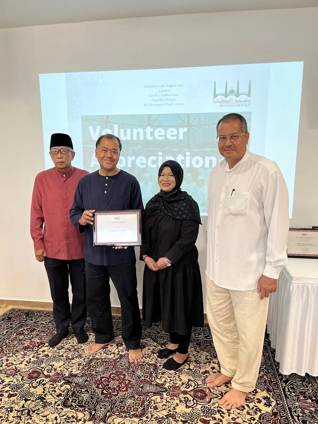 A Raudhatul Jannah member receiving volunteer recognition at a mosque programme